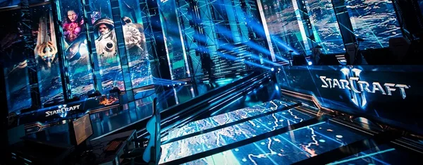 Scène futuriste d'un tournoi d'e-sport montrant de grands écrans affichant les personnages et le logo de StarCraft II lors d'un événement Blizzard.