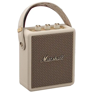 Enceinte bluetooth portable Marshall Stockwell III de couleur crème avec sa grille dorée et sa poignée de transport, sur fond neutre.