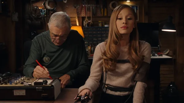 Ariana Grande en blonde, connectée à un moniteur de pression artérielle, tandis qu'un homme âgé prend des notes lors d'une scène de la bande-annonce de 'Focker In-Law'.