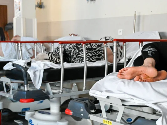 Service des urgences de Nancy lors d'une canicule montrant plusieurs patients sur des brancards, avec une mise en avant sur les pieds d'une personne âgée en premier plan.