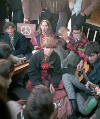 Un groupe de jeunes musiciens jouant de la guitare acoustique et chantant lors de l'été de l'amour en 1967, avec un signe de paix visible