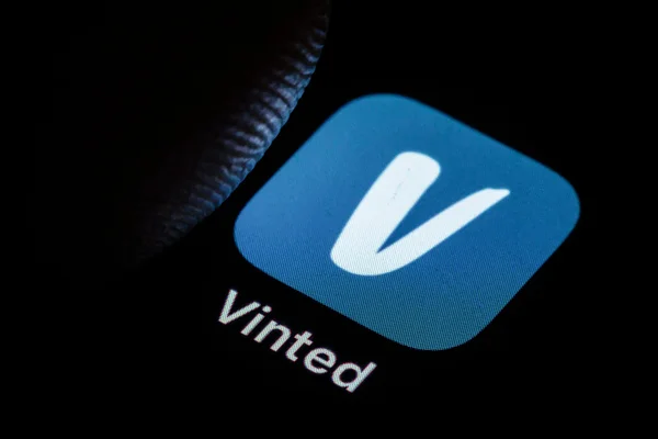 Vue rapprochée de l'icône bleue de l'application Vinted sur un écran de smartphone, dans le contexte des soupçons de trafic d'enfants sur la plateforme et de l'ouverture d'une enquête par le parquet de Nanterre.