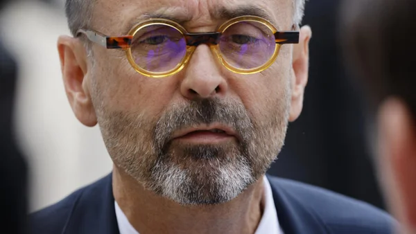 Robert Ménard, maire de Béziers, en costume sombre avec lunettes jaunes, écoutant attentivement lors d'une audition liée à son refus de célébrer un mariage sous OQTF.