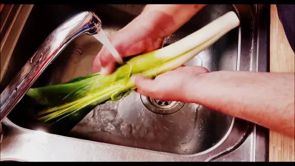 Tutoriel en ligne montrant les étapes pour laver et couper un poireau, avec des instructions pratiques de cuisine pour les gestes de chef.
