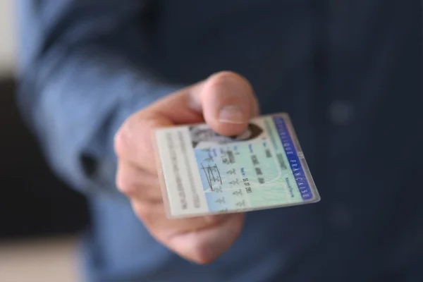 Un jeune homme montrant sa carte nationale d'identité, illustrant la démarche de demande ou de renouvellement d'un document officiel.