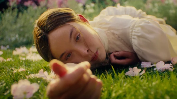 Ella Beatty dans la bande-annonce de la série Netflix 'Monstre : L'histoire de Lizzie Borden', avec un regard intense et un teint écarlate.