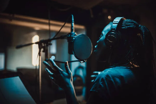 Chanteuse noire chantant avec émotion dans un microphone dans un studio d'enregistrement