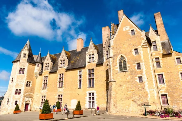 Le château de Baugé en pierre blonde avec ses toits d'ardoise pentus, lucarnes et cheminées en brique, des visiteurs sur le parvis sous un ciel bleu nuageux