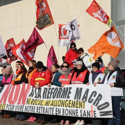 Manifestants au Mans le 7 février 2023 derrière une banderole « Non à la réforme Macron, ni recul ni allongement » avec drapeaux lors d'une manifestation contre la réforme des retraites