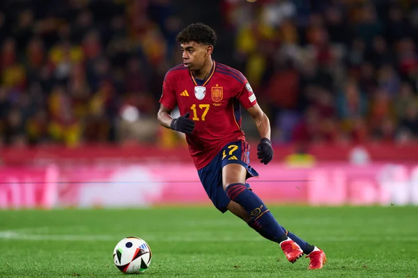 L'attaquant de Barcelone portant le maillot rouge et bleu avec le numéro 17 contrôle un ballon sur un terrain vert pendant un match
