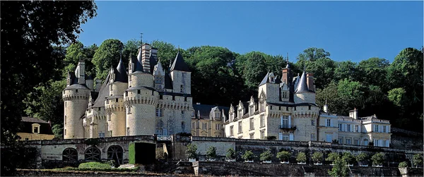 Le château d'Ussé, dit château de la Belle au Bois Dormant en Loire, avec ses tours rondes et toits d'ardoise adossé à une colline boisée au-dessus de jardins en terrasse sous un ciel bleu