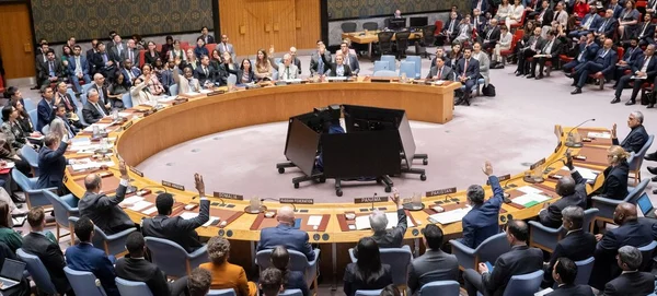 Délégués assis autour de la table en fer à cheval de la salle du Conseil de sécurité de l'ONU, plusieurs levant la main lors du vote d'une résolution condamnant les attaques iraniennes