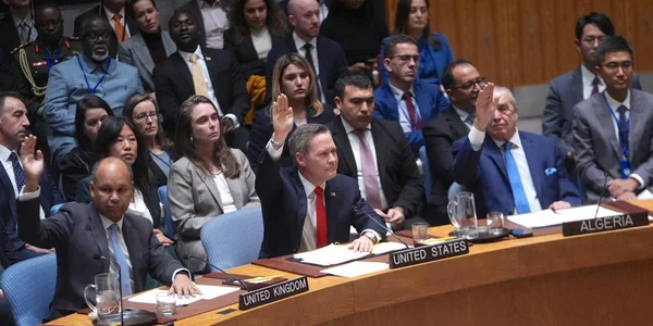 Délégués des États-Unis, du Royaume-Uni et de l'Algérie levant la main pour voter lors d'une session officielle du Conseil de sécurité de l'ONU dans sa salle lambrissée