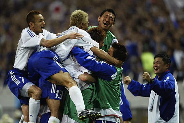 Takayuki Suzuki du Japon entouré par ses coéquipiers après avoir marqué le premier but contre la Belgique lors du match du groupe H de la Coupe du monde