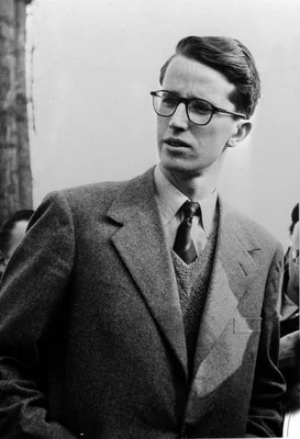 Portrait en noir et blanc du roi Baudouin de Belgique, vêtu d’un costume, d’un gilet de costume et d’une cravate, regardant légèrement de côté avec une expression sérieuse. Le roi a régné de 1951 et s’est marié à Fabiola de Mora y Aragon.