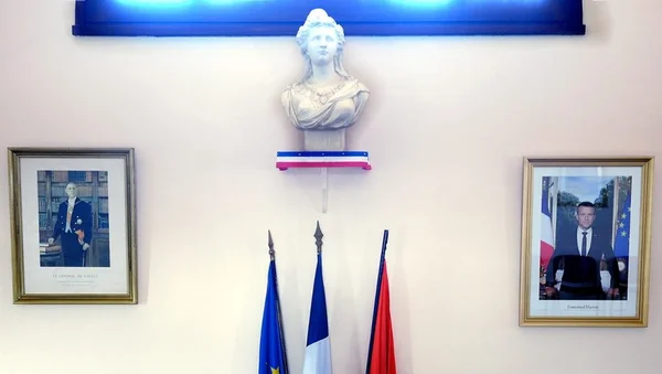 Salle du conseil municipal de Drémil-Lafage avec buste de Marianne, portraits encadrés de Charles de Gaulle et d'Emmanuel Macron, et trois drapeaux dont ceux de l'UE et de la France.