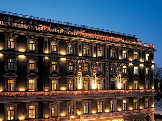 Le Grand Hotel Europe à Saint-Pétersbourg illuminé la nuit, avec un éclairage architectural chaleureux et des guirlandes lumineuses le long du toit et des balcons.