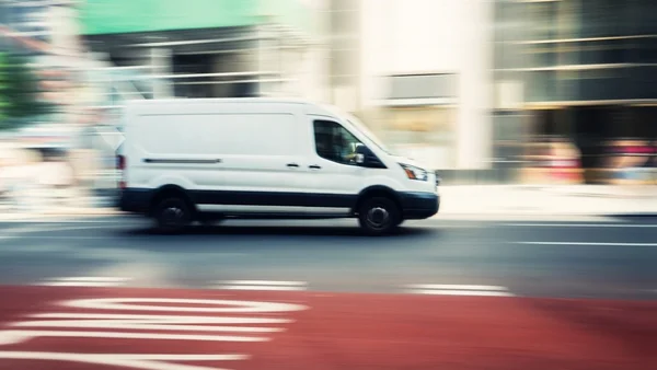Une camionnette blanche en mouvement sur une rue urbaine, sujet central du mythe de l'enlèvement d'enfant et de ses origines