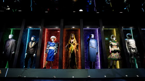 Sept mannequins costumés en personnages de Hunger Games, chacun présenté dans une alcôve colorée et éclairée lors de l'exposition au musée Rodin