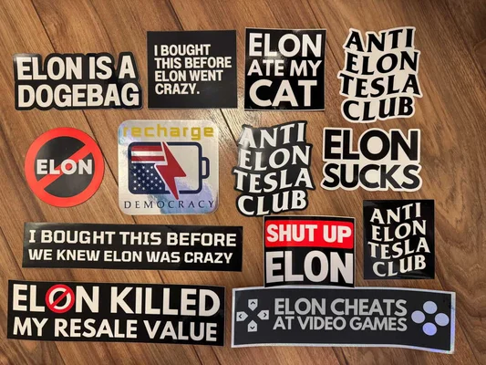Collection d'autocollants antimusks et anti-Tesla disposés sur une surface en bois, avec des slogans critiques envers Elon Musk