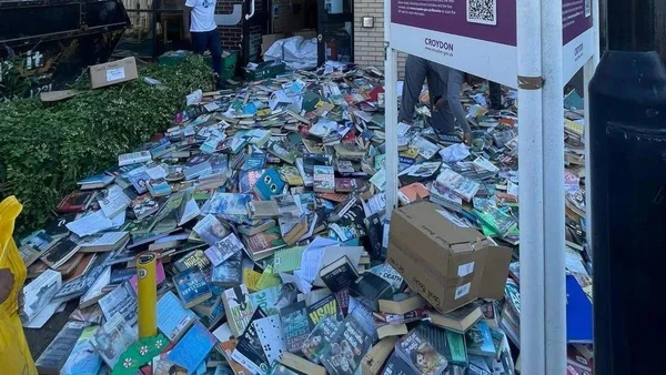 Pile de livres et magazines abandonnés jonchant le trottoir à Croydon à côté d'une affiche du conseil municipal