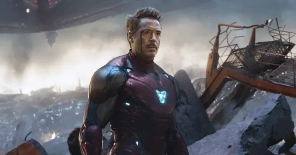 Robert Downey Jr. en armure endommagée rouge et or d'Iron Man sur un champ de bataille embrumé de fumée et de débris dans Avengers: Endgame