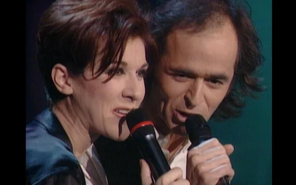 Céline Dion et Jean-Jacques Goldman chantant ensemble côte à côte au micro, lors d'une performance en duo