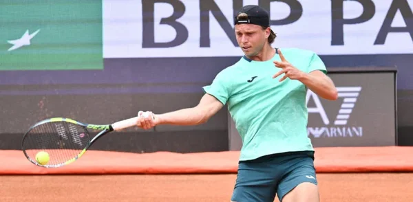 Alexandre Müller, tennisman, en mouvement pendant un échange sur un court de terre battue de Roland Garros, avec la bannière BNP Paribas en arrière-plan