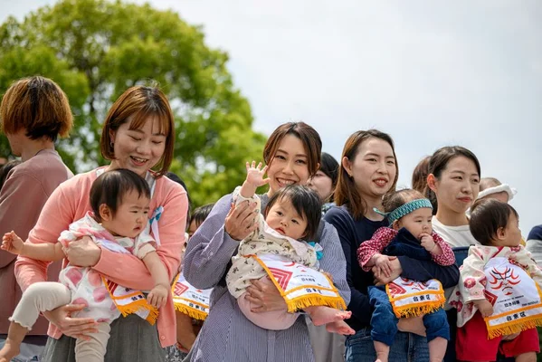 Mères d'enfants en tenue de sumo avant le début du concours de bébés qui pleurent au temple Sensoji à Tokyo le 26 avril 2025