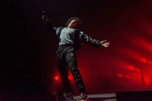 Le rappeur Rilès en concert aux Vieilles Charrues de Carhaix, bras écartés et micro à la main sous les projecteurs rouges de la scène