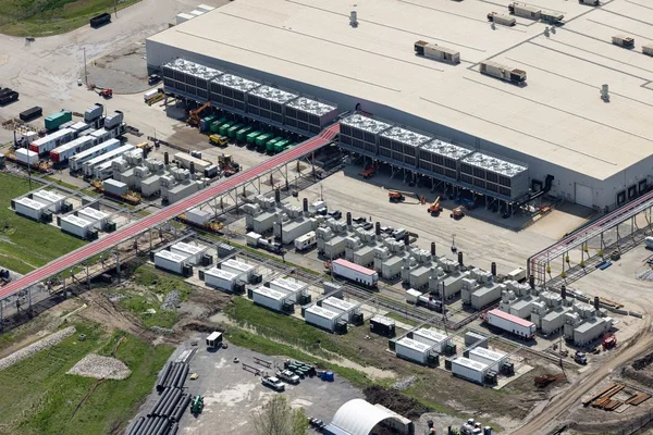 Vue aérienne du data center de xAI à Memphis, montrant un toit blanc avec des rangées d'unités modulaires de refroidissement et un passerelle rouge surélevée.