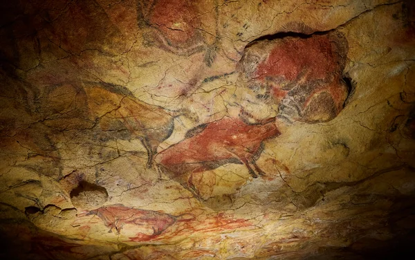 Peinture rupestre préhistorique représentant des bisons et des chevaux en pigments rouges et noirs sur une paroi de grotte fissurée
