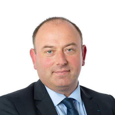 Portrait du sénateur Laurent Duplomb de la Haute-Loire, en costume sombre et cravate, souriant sur un fond blanc