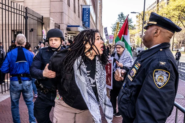 Une manifestante portant un keffiyeh est retenue par deux policiers new-yorkais lors d'une manifestation pro-palestinienne devant l'université Columbia à New York, le 22 avril 2024