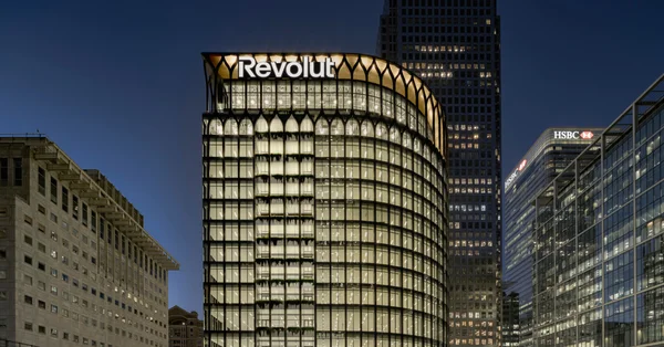 Siège social de Revolut dans le quartier financier de Canary Wharf à Londres, bâtiment moderne illuminé la nuit avec le logo Revolut en haut