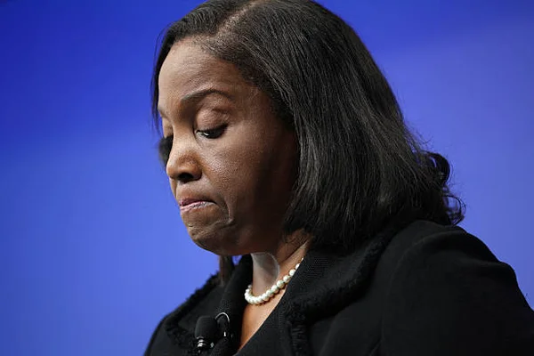 Lisa Cook, membre du conseil des gouverneurs de la Réserve fédérale, vêtue d'une veste noire et d'un collier de perles, regard baissé devant un fond bleu au Brookings Institution