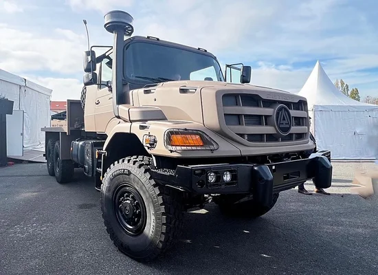 Camion tout-terrain Mercedes-Benz Zetros de couleur sable présenté par Arquus, avec pneus hors-route de grande taille, garde au sol élevée et snorkel d'admission d'air, stationné sur une chaussée.