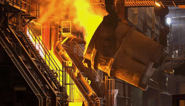 Poche de coulée suspendue à une grue versant du métal en fusion incandescent dans un haut-fourneau de l'usine sidérurgique de Salzgitter, en Allemagne