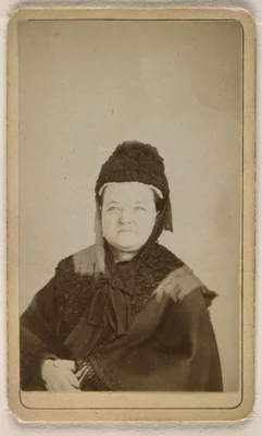 Double exposition photographique de Mary Todd Lincoln en manteau noir et bonnet, avec la figure blanche en fantôme d'Abraham Lincoln apparaissant derrière elle