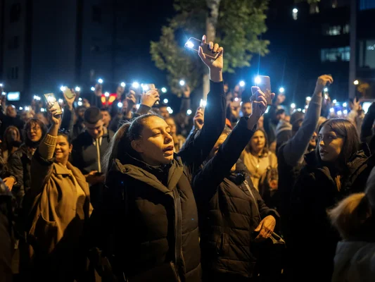 Foule de manifestants serbes de nuit levant leurs smartphones avec les lampes torches allumées, illuminant la scène lors de grandes protestations populaires