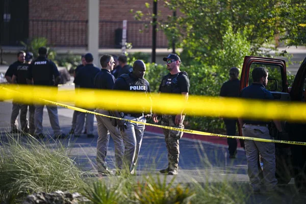 Officiers de police en tenue tactique marquée POLICE se tenant derrière un ruban jaune de scène de crime près de l'université d'État de Floride à Tallahassee