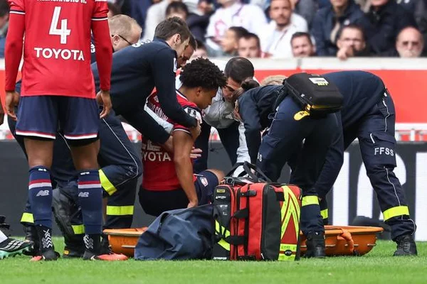 Tiago Santos allongé sur la pelouse et pris en charge par le personnel médical, civière et sacs de soins posés à côté, après le tacle d'Amir Richardson lors d'un match