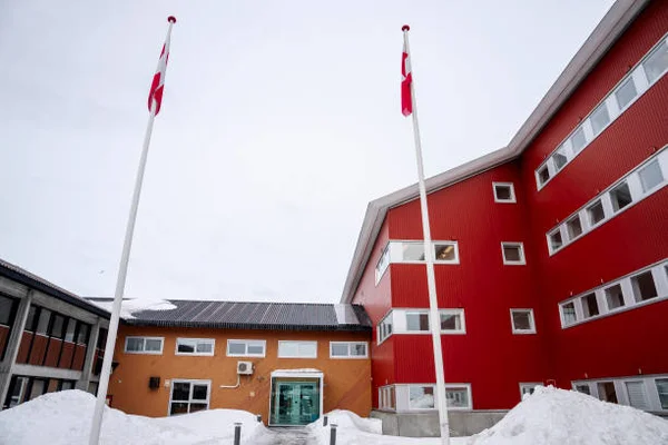 Le bâtiment du parlement groenlandais Inatsisartut à Nuuk, complexe architectural rouge et orange avec deux mât de drapeaux, entouré de neige en mars 2025, après la victoire des démocrates de centre droit aux élections législatives groenlandaises