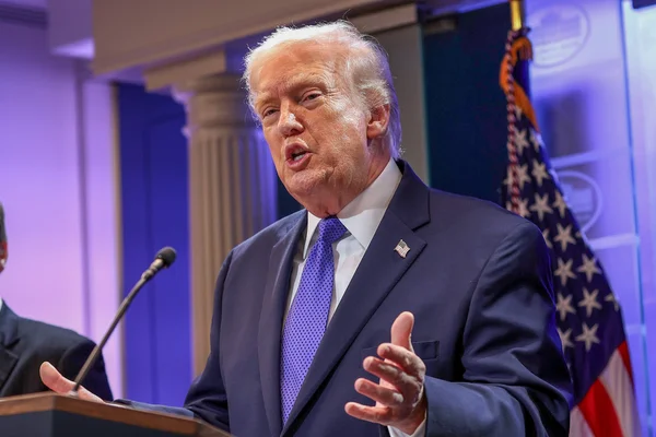 Donald Trump parlant au podium avec le drapeau américain en arrière-plan lors d'une conférence de presse à la Maison Blanche sur la décision de la Cour suprême annulant ses tarifs mondiaux