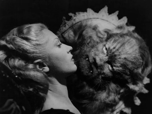 Photographie en noir et blanc de La Belle et la Bête de Jean Cocteau : une femme en profil face à une bête couronnée, leurs visages rapprochés lors du ciné-concert au Théâtre du Châtelet