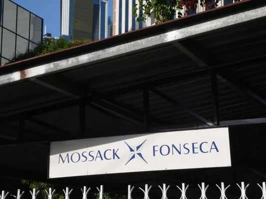 Enseigne blanche portant le nom du cabinet d'avocats Mossack Fonseca en lettres bleues avec son logo, fixée sous un auvent métallique sombre devant le bâtiment à Panama
