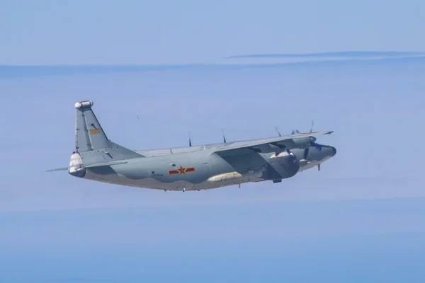 Un avion de transport militaire chinois Y-8, quadrimoteur à turbopropulseurs de couleur grise et frappé d'une étoile rouge, volant dans un ciel bleu dégagé