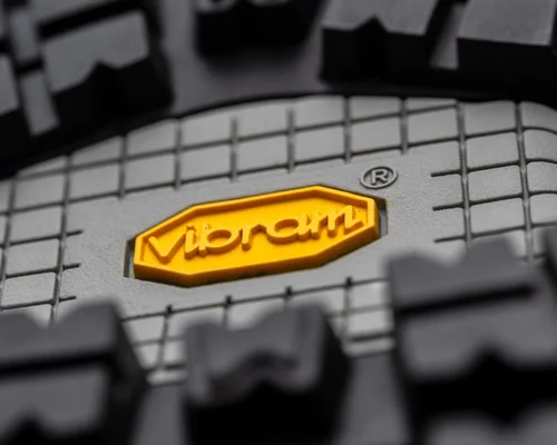 Gros plan sur la semelle d'une chaussure de randonnée Vibram, avec son logo jaune intégré aux crampons.