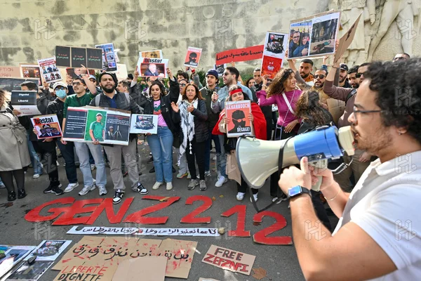 Des jeunes Marocains de la diaspora réunis à Paris en solidarité avec le mouvement GenZ 212, un homme s'exprimant au mégaphone face à la foule devant des pancartes en arabe et en français affichant des portraits de détenus.