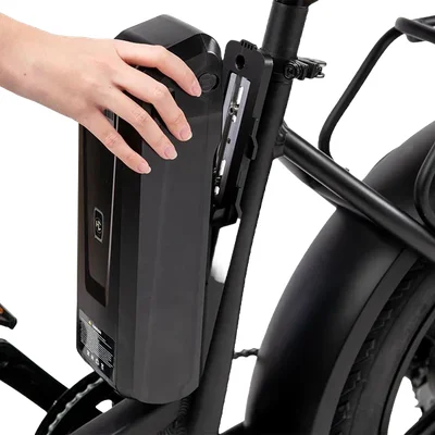 Main humaine extraient une batterie noire intégrée dans le cadre d'un vélo électrique, détail de l'installation et de la conception du véhicule.